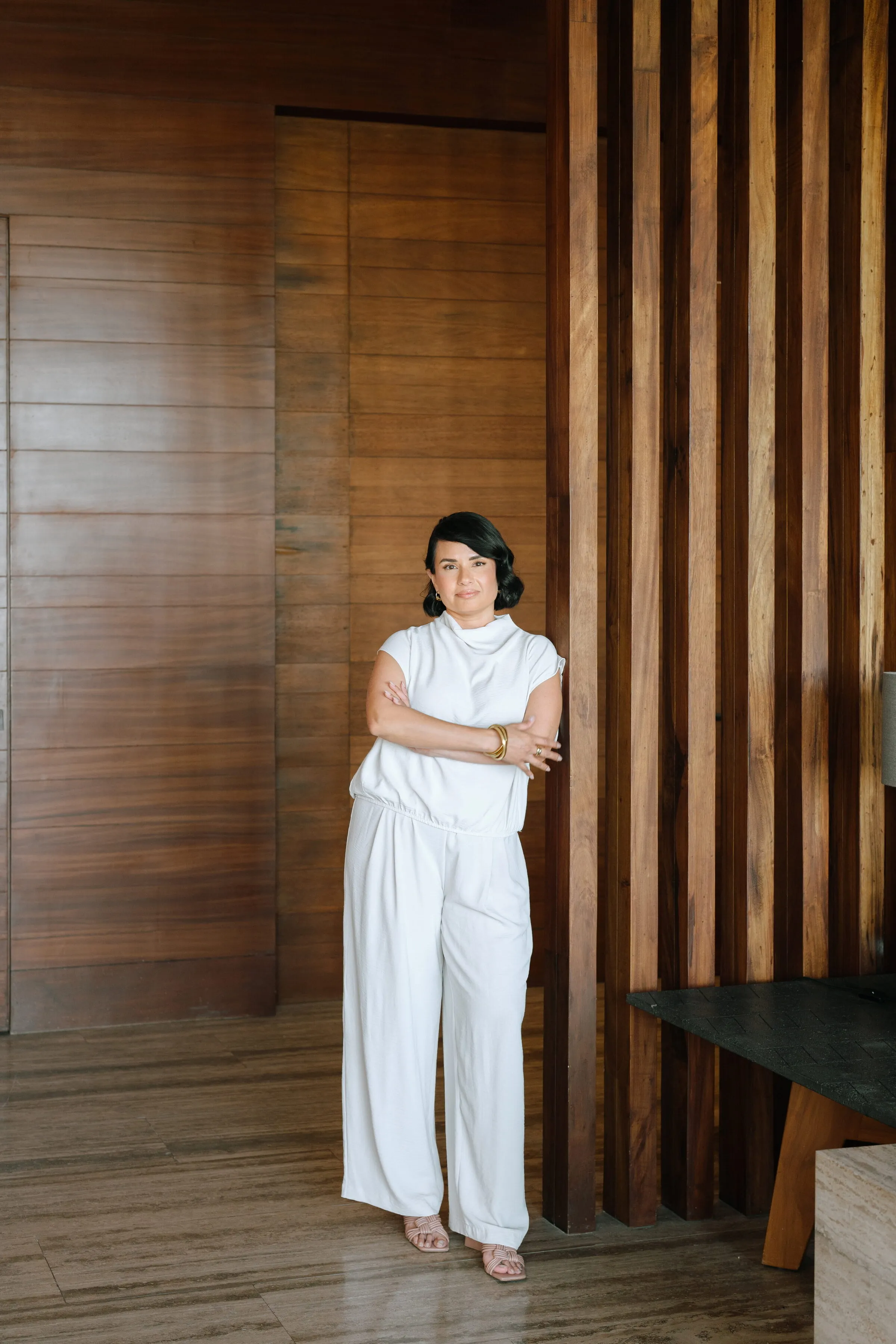 Arianna Ocampo in a white suit against a slatted wood wall