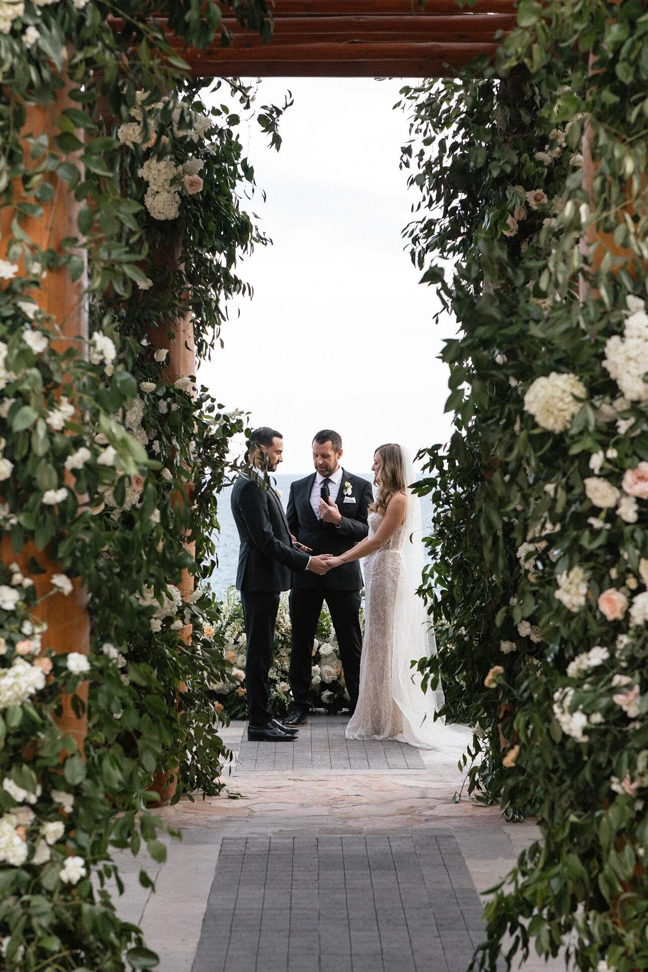 A ceremony framed by a greenery arch that opens onto the sea at Waldorf Astoria Los Cabos