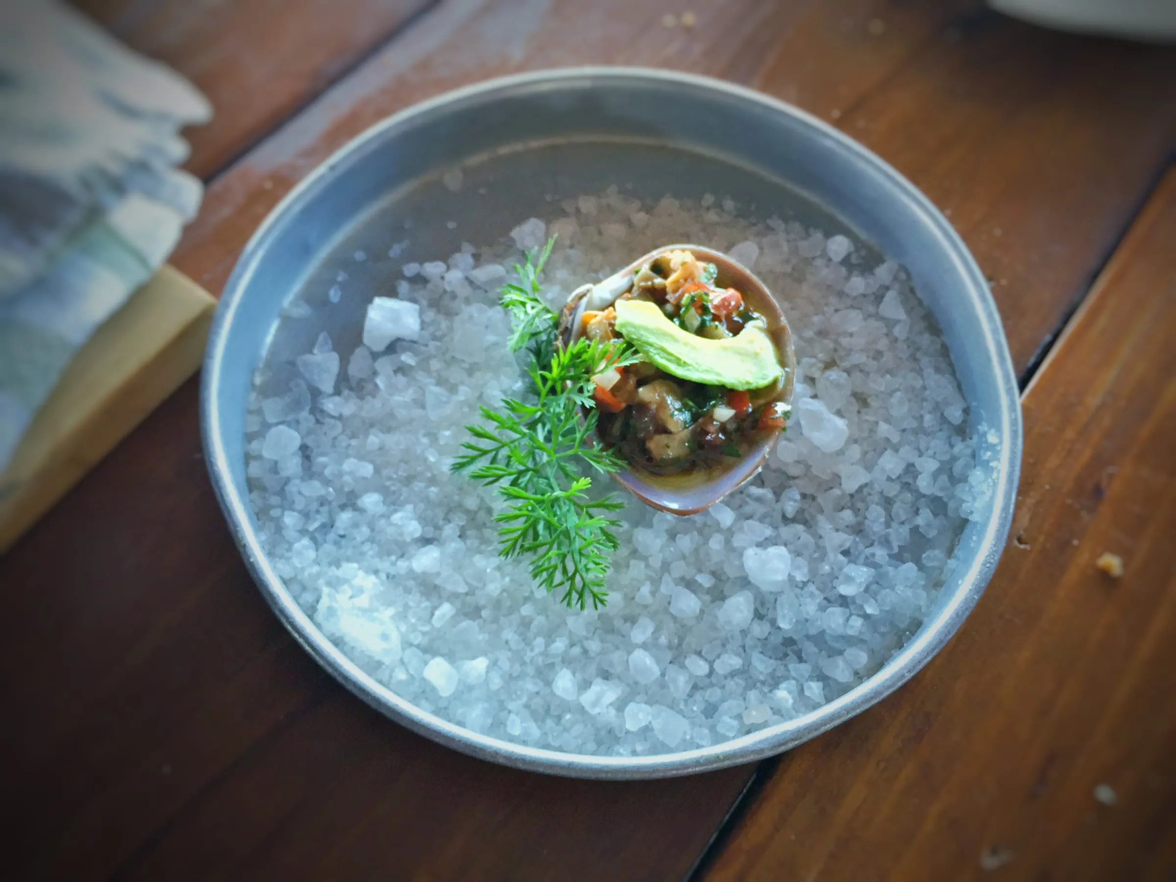 Chocolate clam ceviche served in a glass over crushed ice