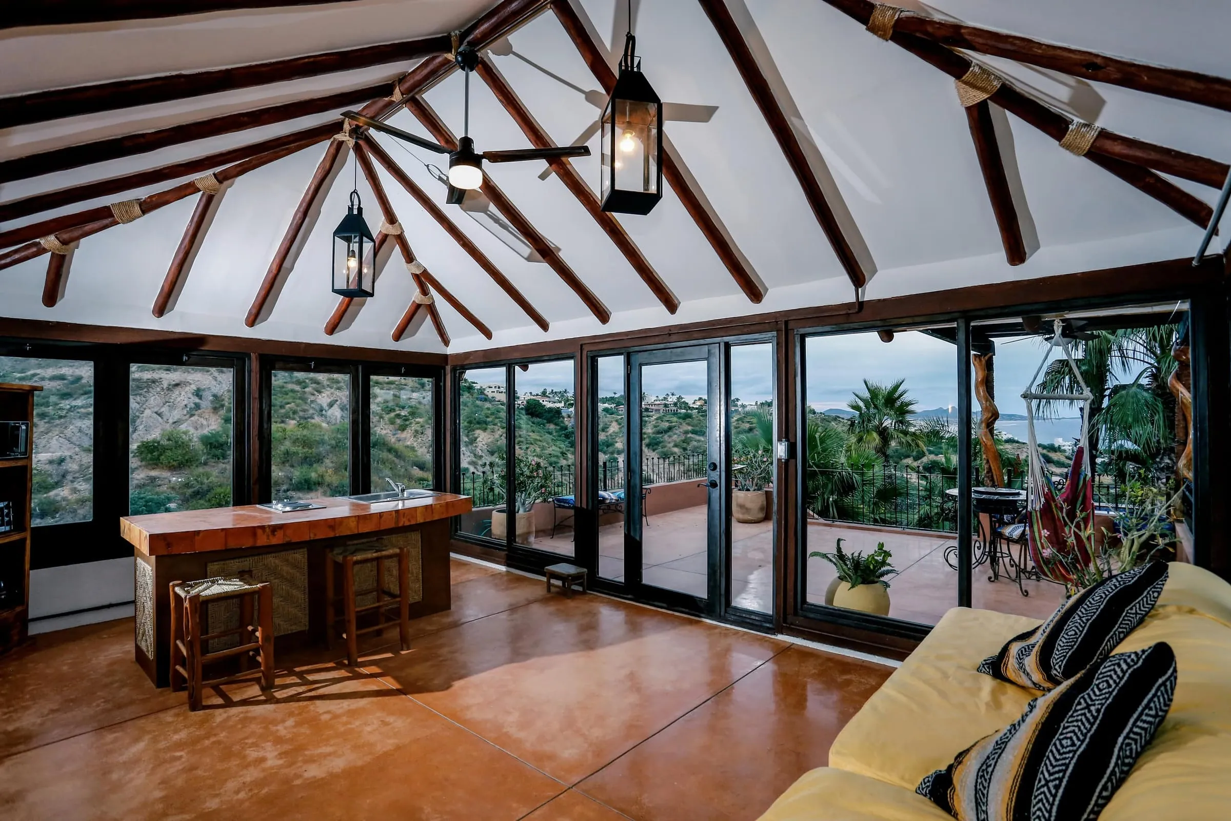 The living room under an open beamed ceiling, glass doors along one wall